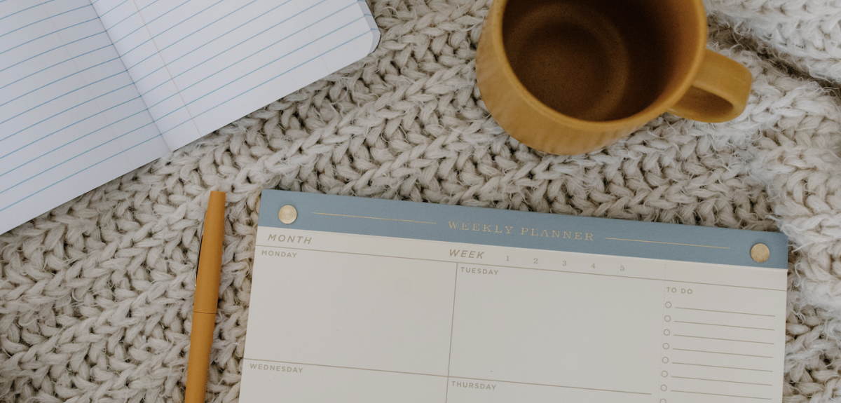 A planner with a coffee cup and blanket. Photo by Tara Winstead from Pexels