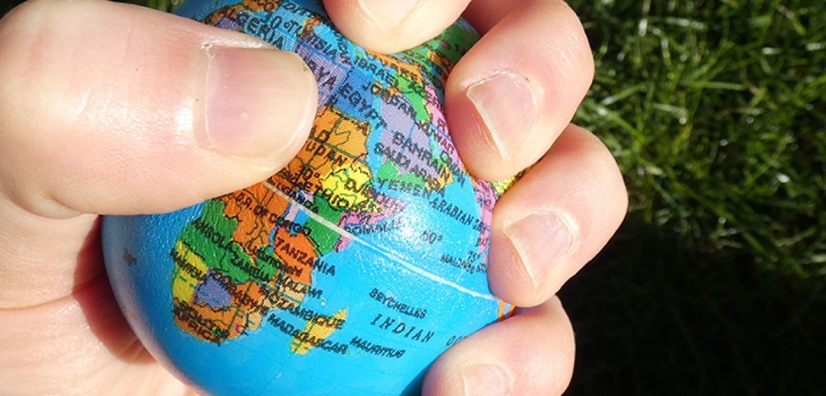 A hand squeezing a planet Earth stress ball. 