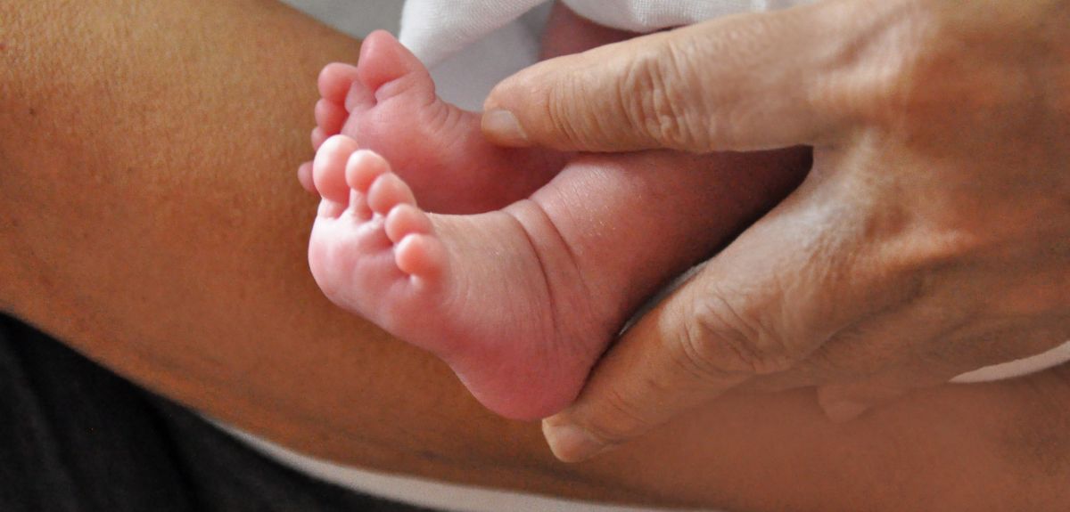 Newborn baby feet held by adult