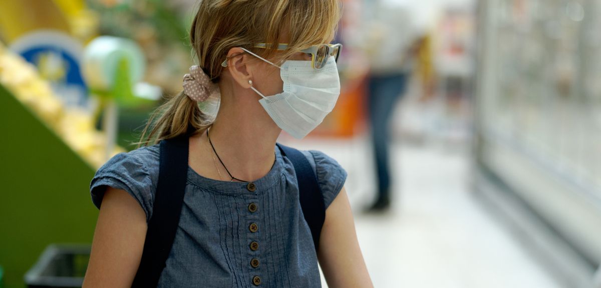 Woman shopping in a supermarket wearing a face mask, as new regulations requiring face coverings are announced