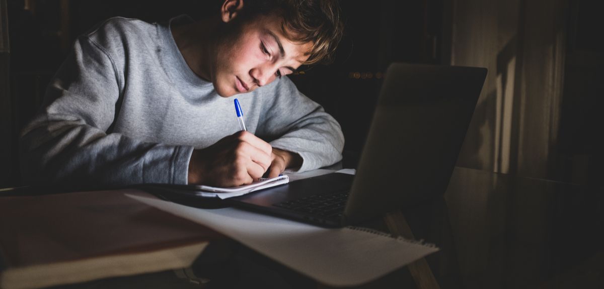 Teenage boy working on school work in front of laptop