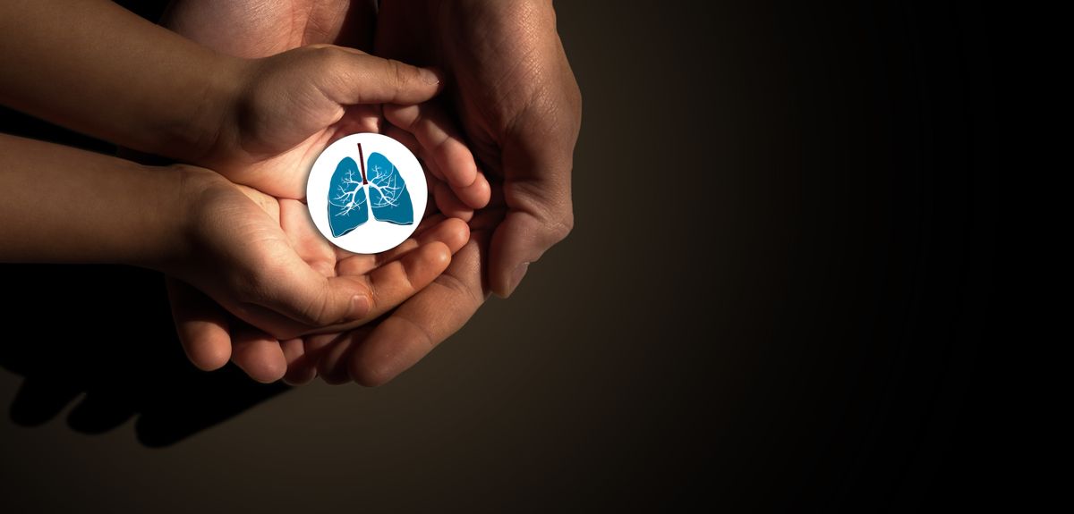 An adult and child's hands holding a picture of lungs