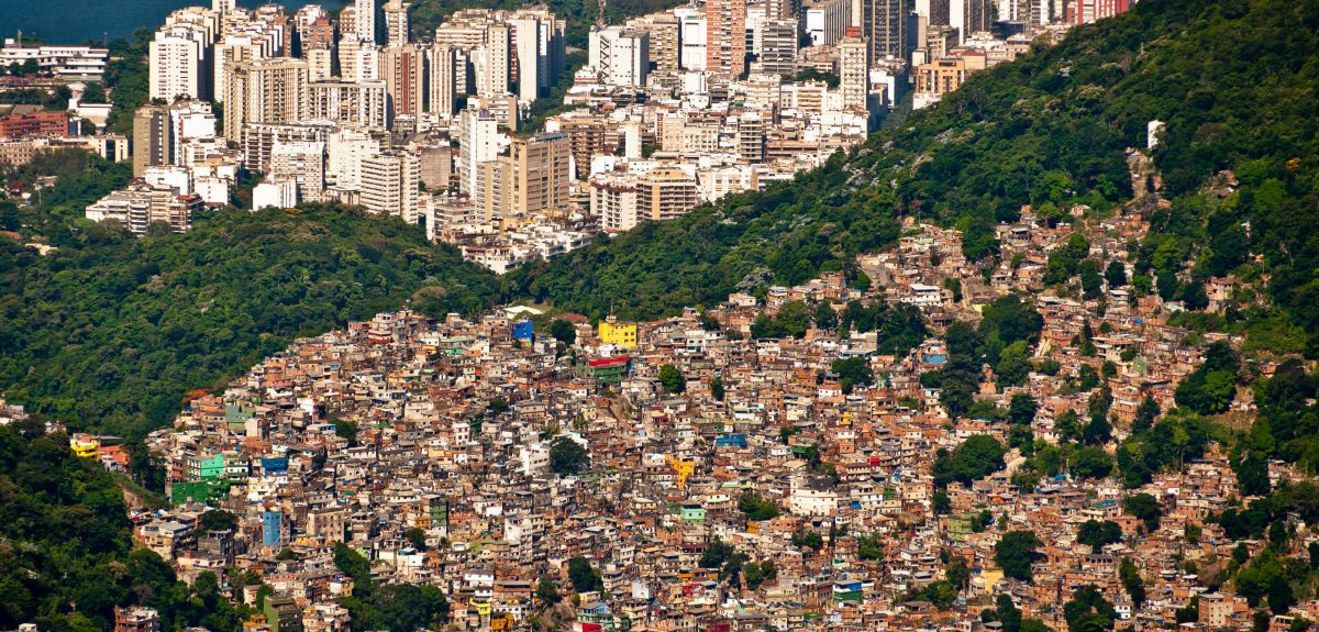 Aerial view of Favela da Rocinha, Biggest Slum in Brazil on the Mountain in Rio de Janeiro, and Skyline of the City behind