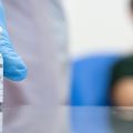 Close up of vaccine vial with patient in background