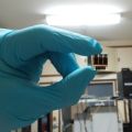 A gloved hand holds a perovskite cell up to the light.