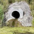 A wastewater pipe in a river bank dishcharges a stream of dirty water into a river. 