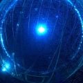 A round chamber with walls made up of photomultiplier tubes, illuminated by a central blue light.