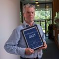 Photo of Professor John Todd holding prize certificate
