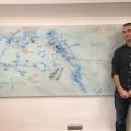 Greger Larson stands next to a white board on which Angela Perri and David Meltzer mapped archaeological sites and populations of dogs and people. The two day effort resulted in new insights into the close relationships and joint histories of the two spec