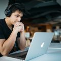 Man in headphones on Apple laptop
