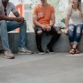 Four people sitting on a concrete wall. Photo by Kate Kalvach on Unsplash.