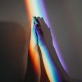 Hands joining in rainbow light. Image credit: Cottonbro / Pexels.