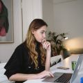 Female sat at a desk on a laptop in a black top. Image by Polina Zimmerman on Pexels.