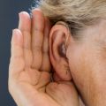 Photo | Elderly woman with hearing aid on grey background. Close up.