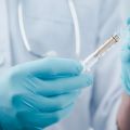 Doctor wearing gloves holding a vial of vaccine and syringe