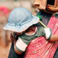 Young mother in Africa carries baby on her back